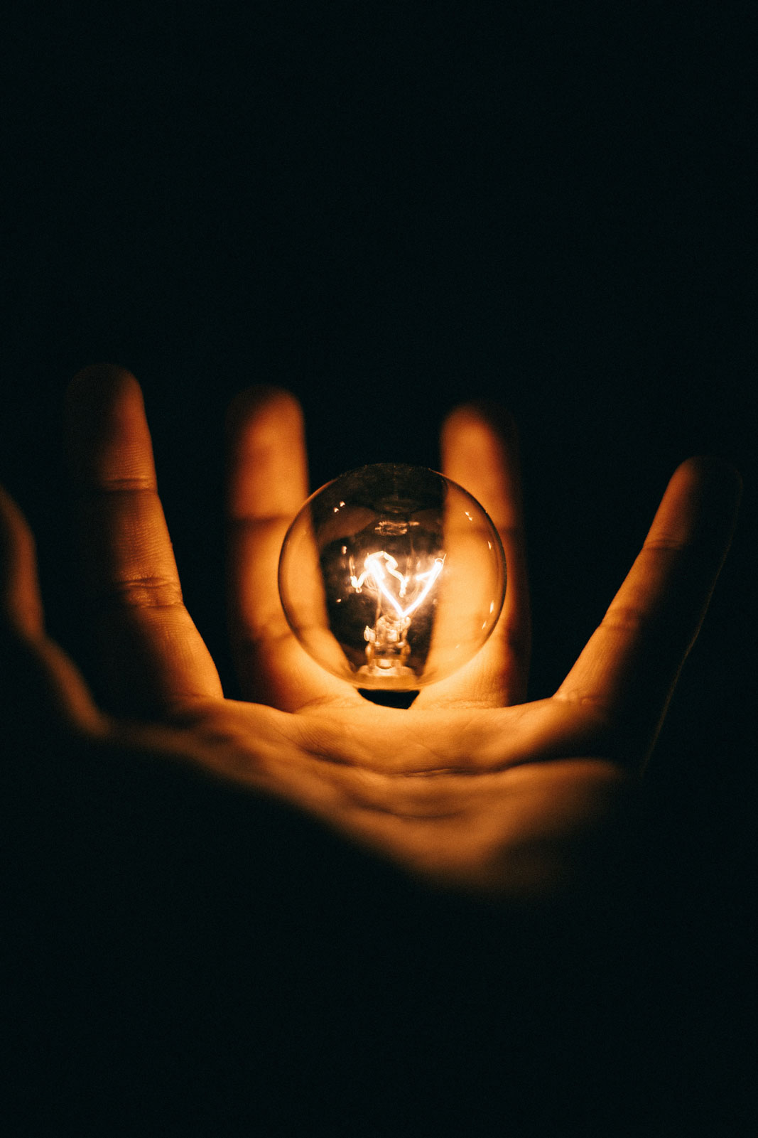glowing lightbulb inside of a hand